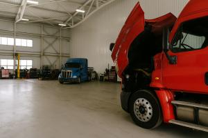 Interior view of a commercial truck repair shop with a white semi-truck parked inside for maintenance, illustrating professional repair services in action.