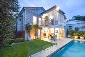 Evening view of Hawthorne Queenslander renovation showing pool, landscaped backyard, and covered alfresco dining area connected to interior living spaces.