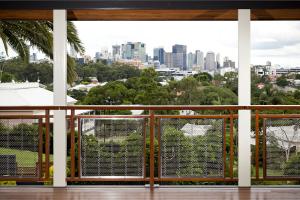 View from a timber-framed verandah in Auchenflower, showing stainless steel wire balustrades and timber handrails with a full panoramic outlook over Brisbane’s city skyline and surrounding greenery.