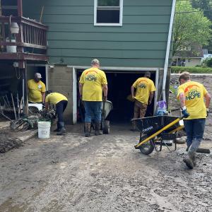 A Few Kimble Volunteers Work with Wheelbarrows to Muck Out a Damaged Home