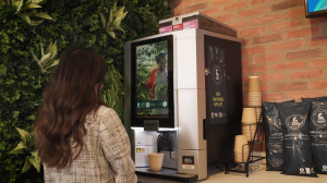 Coworkers enjoying coffee in an office, standing beside a bean-to-cup coffee machine.