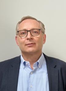 Headshot of Jürgen von Hollen, CEO of Acuriant Techologies, Inc., pictured in a dark suit jacket and a light gray background.