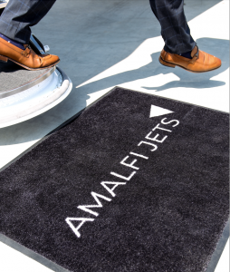 Man walking off private jet with Amalfi Jets Welcome Mat