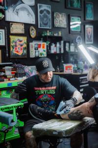 Close-up of tattoo artist Sixer working on a black and gray realism tattoo inside the Escondido-based Golden Child studio.
