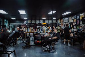 Interior of Golden Child Tattoo studio showing artists at work with clients during a busy session, surrounded by tattoo artwork and equipment.