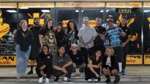 Group photo of Golden Child Tattoo artists and staff standing in front of their Escondido, CA studio exterior under the “Tattoo” signage.