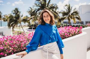 Brooke Davies enjoying a sunny day in Far North Queensland, standing in front of vibrant tropical flowers — representing the lifestyle freedom of her online business.