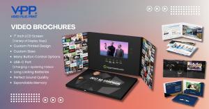 "Hands holding an open Video Brochure with a high-quality printed cover and an embedded LCD screen playing a branded promotional video. The image displays the interactive design, vibrant colors, and tactile print elements that make Video Brochures an enga
