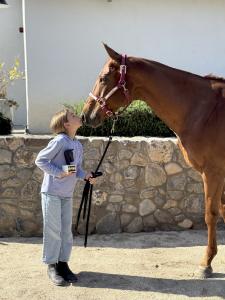 a young girl gives a kiss to her horse who won a prize in an arena polo event