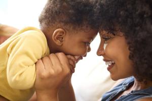 Mother smiling with her child, symbolizing maternal mental health support from The Natural Nanny Collective.