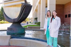 female doctors in white coats stand in front of waterfountain