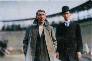 Colorized image of Irish marathon runner Pat White wearing a trench coat, standing in front of a stadium structure with a blurred crowd in the background.