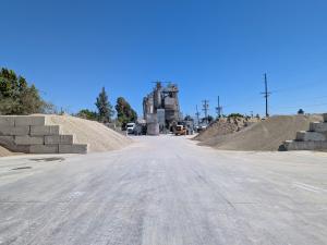 Wide view of a concrete manufacturing site in the San Fernando Valley with gravel piles, mixers, and open access areas, secured using a pole-mounted video surveillance system.