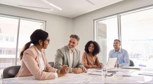 4 businesspeople at table smiling and talking, 2 women and 2 men
