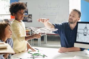 An aeromodeling class teacher explains how quadcopters fly to a youth class