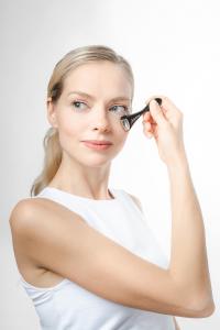 Woman applying Fusion Meso tool under the eye area during a skin booster treatment; represents non-invasive skin booster Singapore solutions for anti-ageing and hydration.