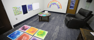 Soaring Eagle Waterpark's colorfully decorated sensory room featuring art on the walls, a round table with craft supplies, and a cozy black armchair.