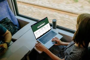 A woman on a train searching SpherewCard Marketplace for a professional on a laptop