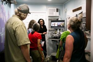 people inside a clinic watch a physician on a screen