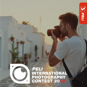 alt="Young photographer taking a photograph in a sunlit, white‑washed lane; Peli International Photography Contest 2025 logo bottom‑left"