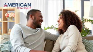 A smiling couple relaxes together on a cozy living room sofa, sharing a joyful moment and looking at each other with warmth and comfort. The background includes bright windows and plants, evoking a sense of well-being and security. The image reflects Amer
