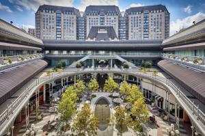 Exterior view of The Crescent office complex in Dallas, featuring a symmetrical layout with French-inspired architecture, a tree-lined courtyard, café seating, and arched retail walkways—highlighting the property involved in LPShares' $1M LP exit.