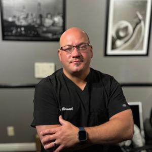 Dr. Jeremy Bernath stands in his chiropractic office in Chino, CA, his arms crossed, looking intently at the camera.