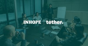 Tether & INHOPE Logo next to each other, seperated by a white vertical line, indicating the strengthened partnership. In the background a conference table with people working under a green transparent overlay.