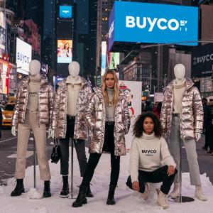 A lively Buyco fashion pop-up event with customers browsing limited-edition activewear in a trendy city venue.