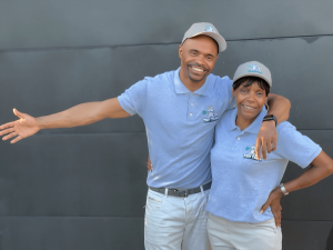 "Nasceas Timms and Bessie Taylor, mother and son co-founders of Tidy Tails Waste Solutions, a family-owned dog waste removal service in Atlanta, GA, standing together in branded uniforms with poop scooping tools."