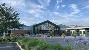 Photo of Hicks Nurseries Storefront featuring a glass facade and LED logo. Summer flowering planters line the building and beautiful plantings around the parking lot