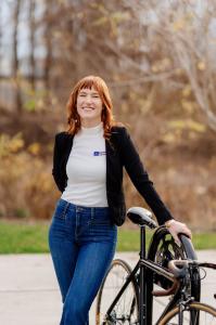 CycleSafe Vice President Hannah Hartger leans on a CycleSafe bicycle rack; 2024.