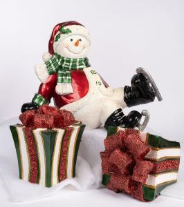 "Festive ceramic snowman in red and green with ice skates, sitting among two glittery holiday gift boxes, styled on soft snow-like fabric—ideal for Scottsdale Christmas interior décor."