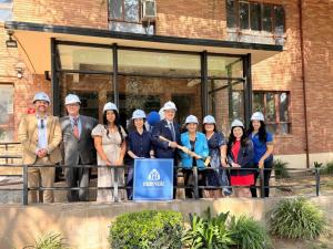 Group of people wearing hard hats stand in front of a brick building at Maryvale in Rosemead, smiling and holding a ceremonial shovel to kick off the Seton House expansion project, which will add 20 new housing units for unhoused women and children.