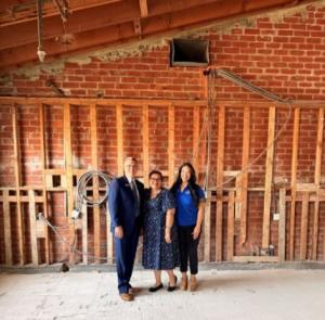 a group of three people stand inside the Laboure Building amid exposed brick where construction is being done for the Seton House expansion project.