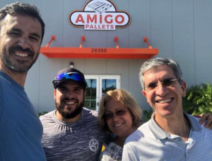 The family behind Amigo Pallets standing outside their South Florida facility, smiling in front of the company building. A representation of their growth from local roots to national reach through innovation and strong partnerships.
