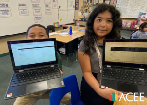 Photo of two students holding laptop computers.