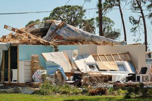 A storm-damaged house with visible structural destruction and debris.