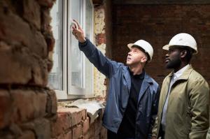 Two restoration professionals conduct damage assessment on-site after storm impact.