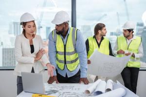 Engineers collaborate in a modern office, reviewing plans and discussing details of a construction project as a unified team.