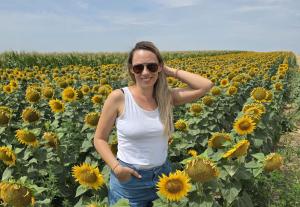 Ana Mitrovic smiling in a field of daisies, representing the freedom and fulfillment of building a successful work-from-home business as a mom using modern tools and AI.