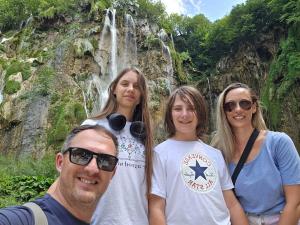 Ana Mitrovic smiling with her husband Goran and their two young children, enjoying family time outdoors. A successful work-from-home mom earning $10K/month through tech-enabled entrepreneurship.