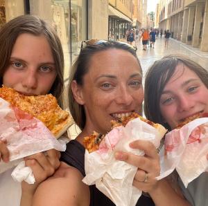 Ana Mitrovic and her children enjoying pizza outdoors on a family vacation, symbolizing the flexibility and joy of a successful work-from-home lifestyle for moms.