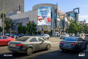 Cars on the street in front of a building with the Christmas in July billboard.