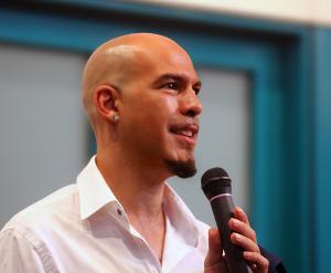 Ivan Pili speaking at an art exhibition, presenting his hyperrealist paintings to the audience