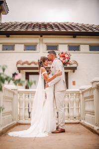 Chelsee Delgado, Miss Melbourne for America, and her fiancé Paul Sample pose on the Tuscan-style balcony at Bonita Ranch, a top-rated wedding venue in Melbourne, Florida. The couple is framed by sunset hues and Mediterranean architecture, capturing 2026 w