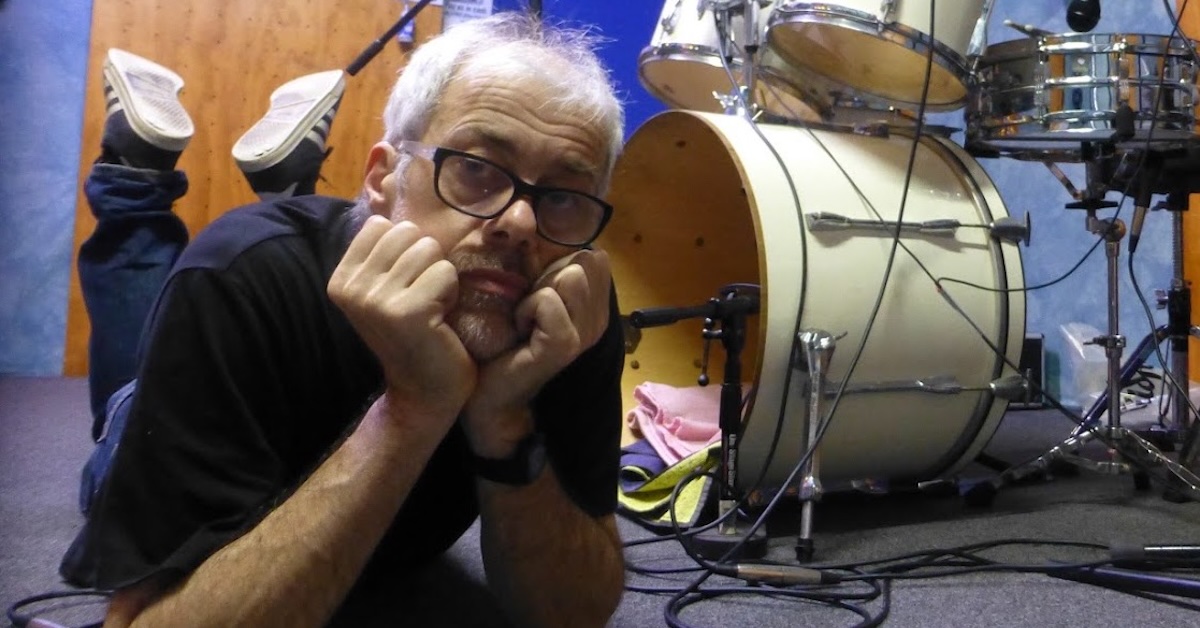 Mark Temple during rehearsal of drums part for Molecular Rock, Mark is Lying on the floor with a drum kit behind him. He is the only person in the studio.