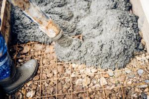 Close-up of a cement pump hose pouring durable concrete mix at a building site.
