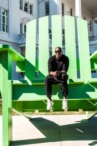 Dave Chappelle sits on the big green Adirondack chair on the front lawn of the Duke Ellington School of the Arts during a 2017 visit to his alma mater in Washington, D.C.
