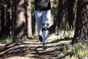 Person running outside while wearing KneeMo®, showcasing active use of the device outdoors.